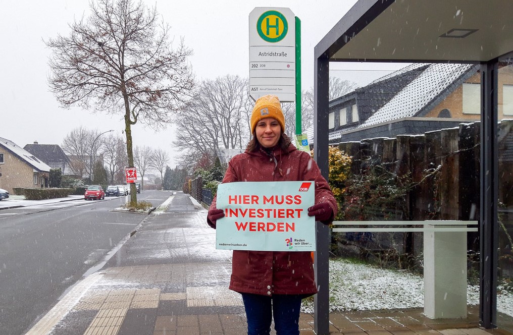 Geschäftsführerin der DGB-Region Ostwestfalen-Lippe Anke Unger in der Stadt Gütersloh mit "Hier muss investiert werden"-Schild.